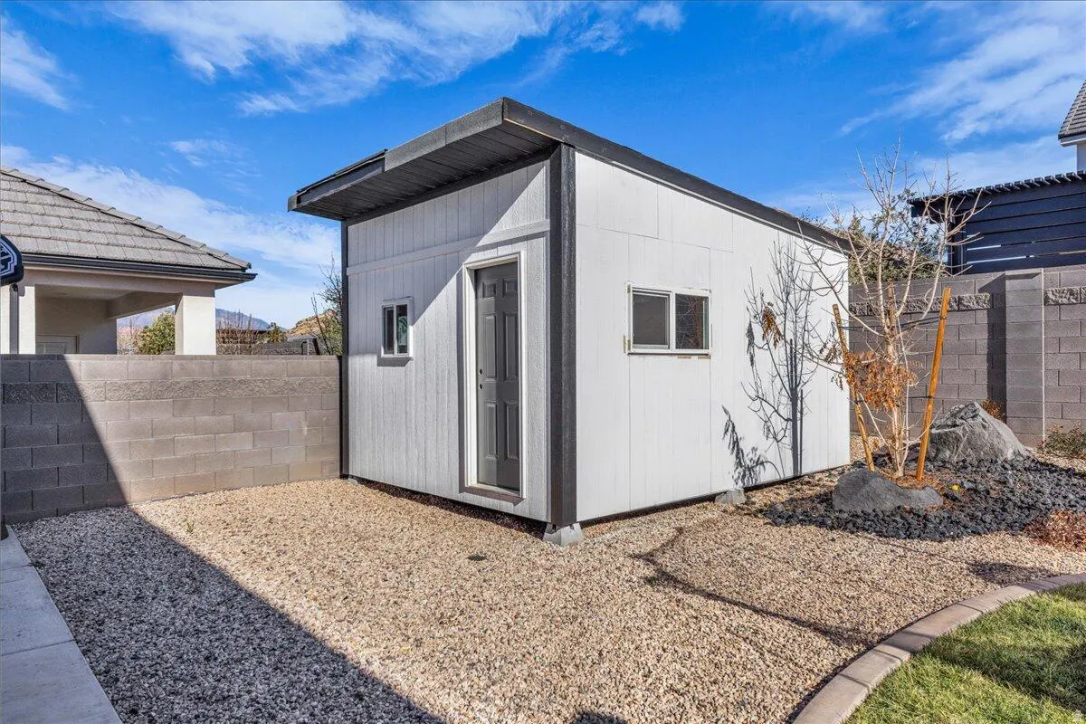 Detached exterior structure featuring white vertical siding, a flat roofline, and a gray entry door