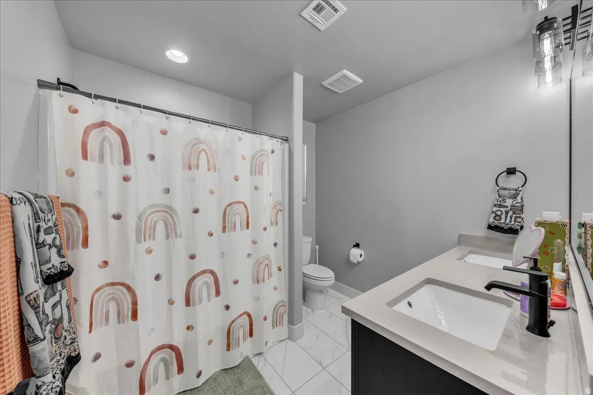 Bathroom featuring a dual vanity with light-toned countertops, contemporary black faucets, and under-mount sinks