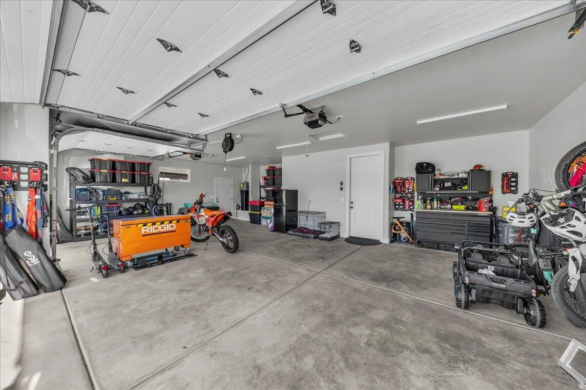 Spacious garage featuring a concrete floor, overhead lighting, an interior access door, and a roll-up garage door with opener