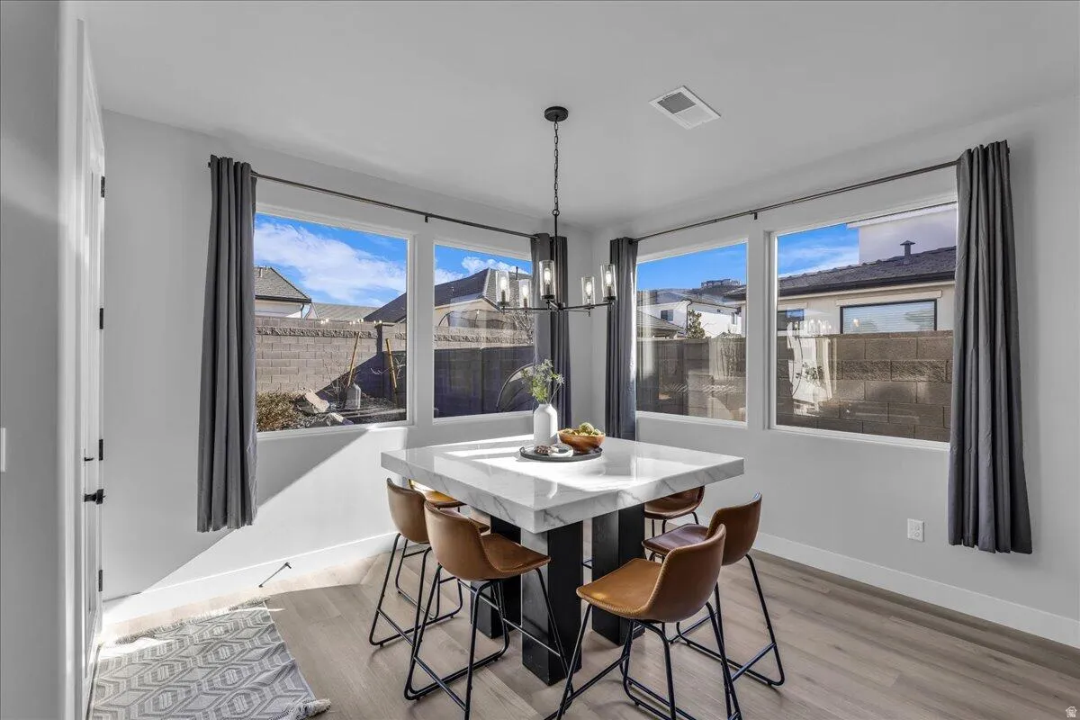 Corner dining area featuring wood-finish flooring and a contemporary chandelier