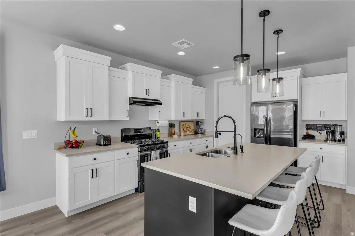 Modern kitchen featuring white shaker cabinetry, stainless steel appliances, a center island with countertop seating, and wood-finish flooring