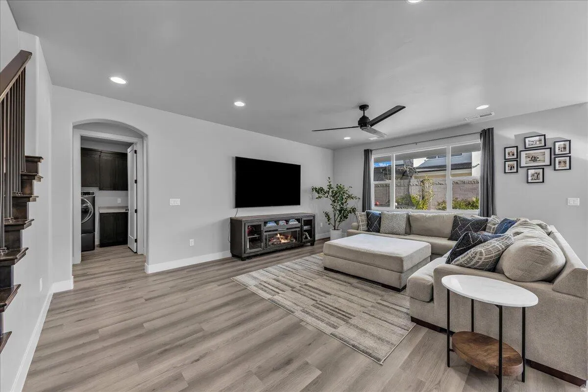 Spacious room featuring wood-finish flooring, recessed lighting, and a modern ceiling fan
