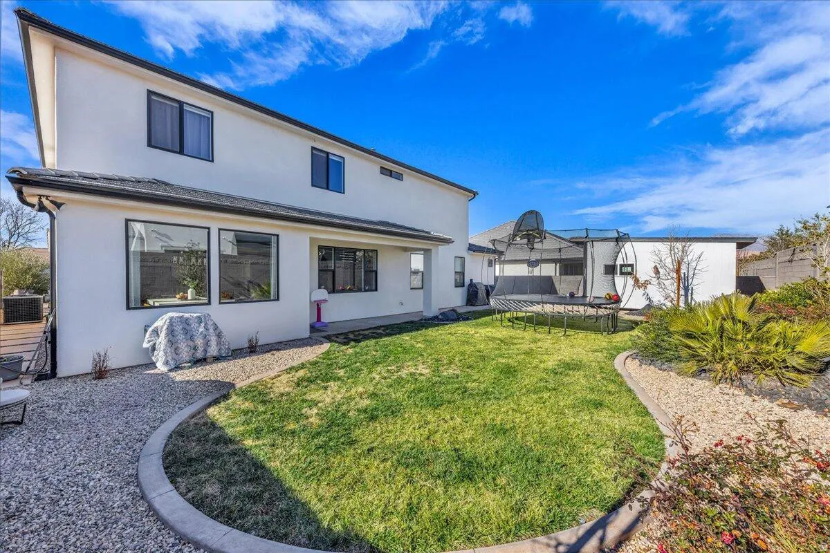 Rear exterior featuring a two-story design with white stucco siding, black-framed windows, and a dark shingled roof