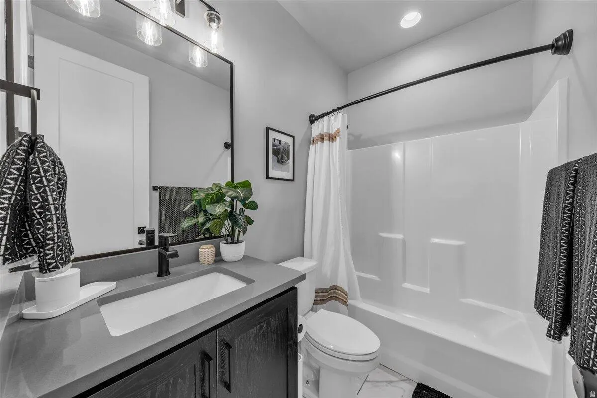 Contemporary bathroom featuring a dark wood-finish vanity with an integrated sink, a large framed mirror, and a full bathtub with a shower kit