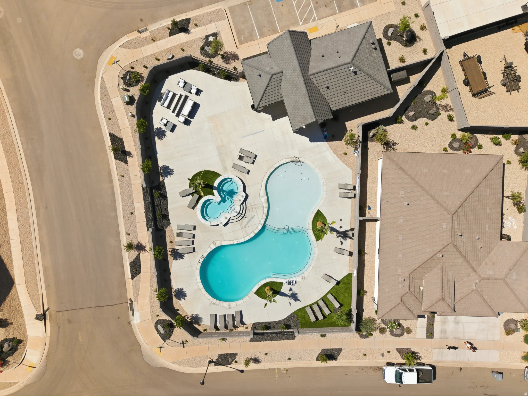 Community swimming pool with an integrated spa, surrounded by a concrete deck and multiple lounge chairs
