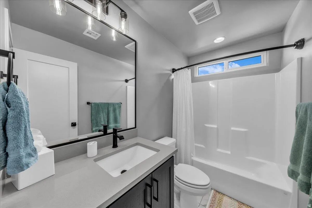 Bathroom featuring a single vanity with a white rectangular sink, dark cabinetry, and a light-toned countertop