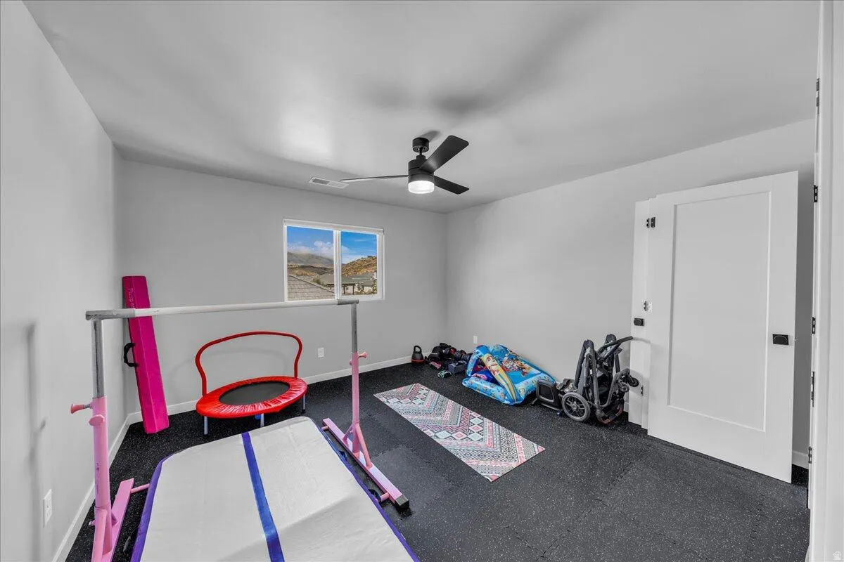 Spacious room featuring durable dark rubber flooring and a contemporary black ceiling fan