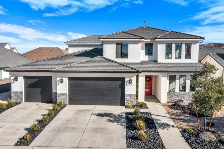 Modern two-story residence featuring a tile roof and a stucco exterior with stone accents