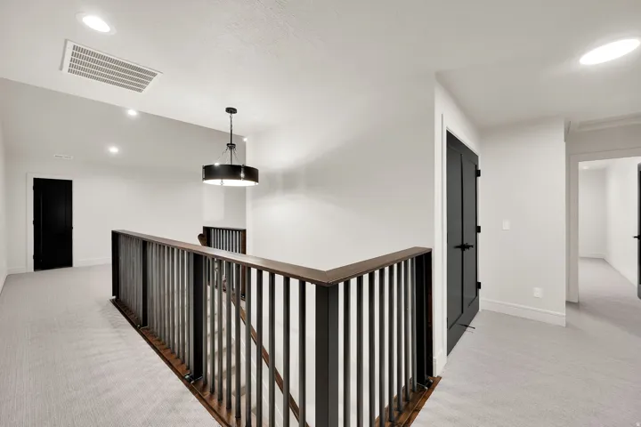 Upper-level landing featuring light-toned carpeting, white walls, and dark-toned doors