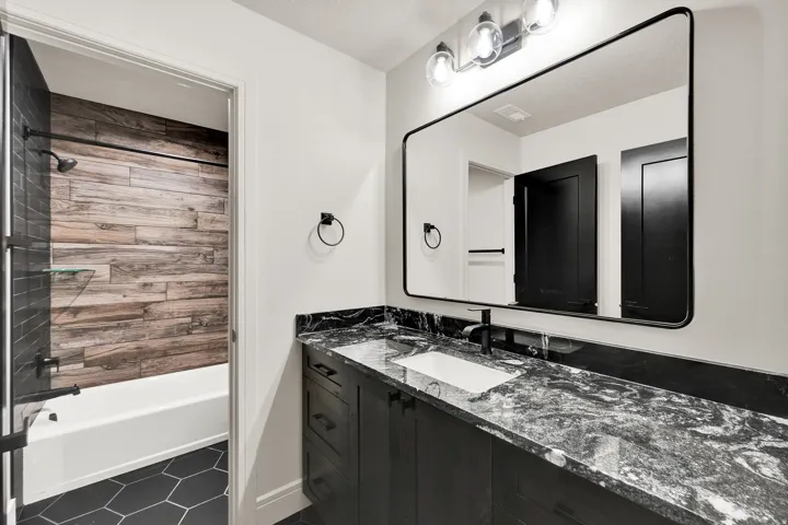 Bathroom vanity featuring a dark stone countertop with integrated sink and modern black faucet