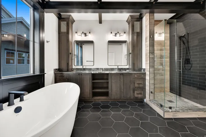 Spacious bathroom featuring a freestanding tub, hexagonal floor tiling, and a glass-enclosed shower with subway tile surround