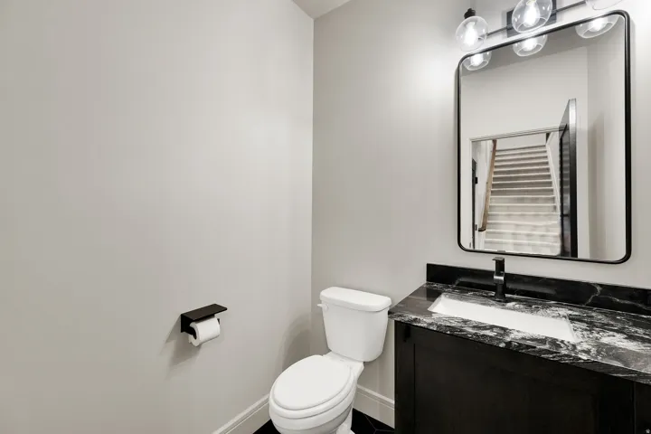 Bathroom featuring a vanity with dark cabinetry, black and white patterned countertop, undermount sink, and a black framed mirror