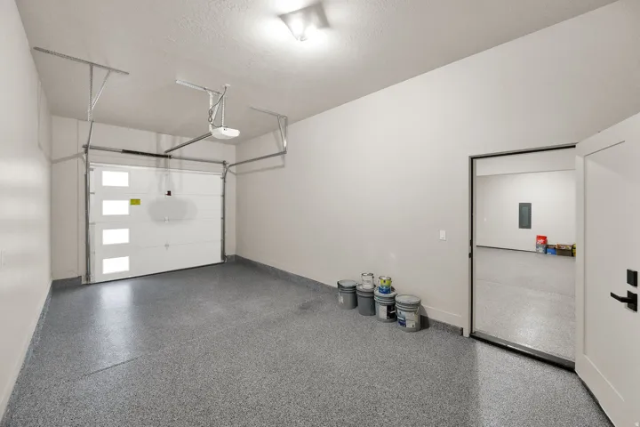 Spacious garage featuring a modern sectional garage door with frosted window panels, an automatic garage door opener, and durable speckled epoxy flooring