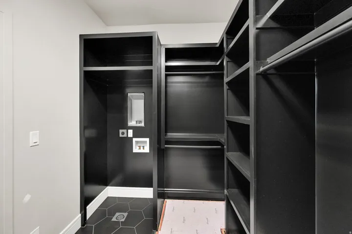 Custom closet system featuring dark cabinetry and extensive shelving