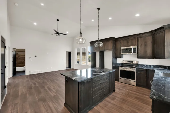 Modern kitchen featuring dark wood cabinetry, stainless steel appliances, and a central island with a contrasting stone countertop