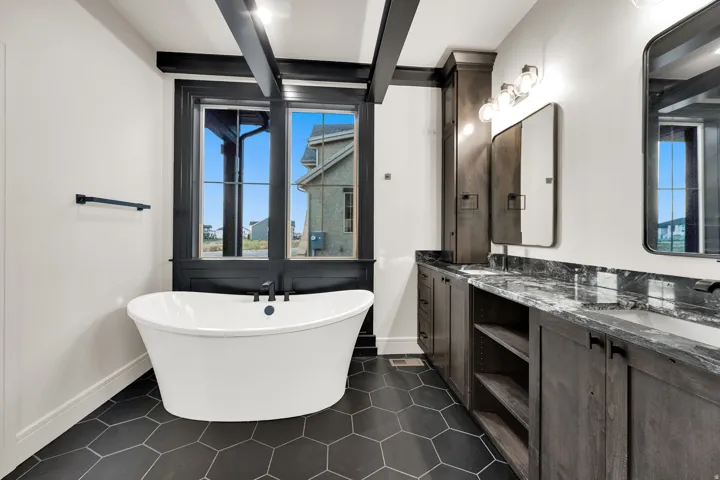 Freestanding soaking tub with black fixtures, set against black-framed windows