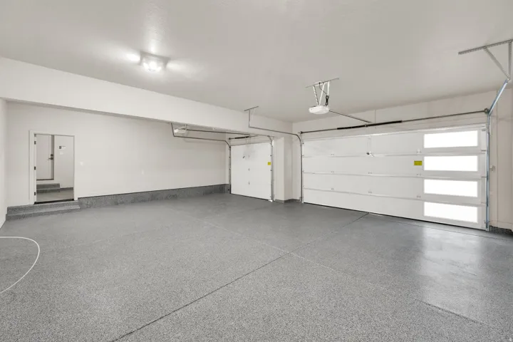 Spacious garage featuring a speckled epoxy floor coating, two overhead garage doors, and direct interior access