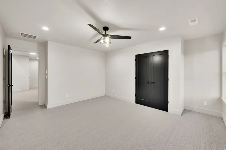 Spacious room featuring light-colored carpeting, recessed lighting, and a modern ceiling fan