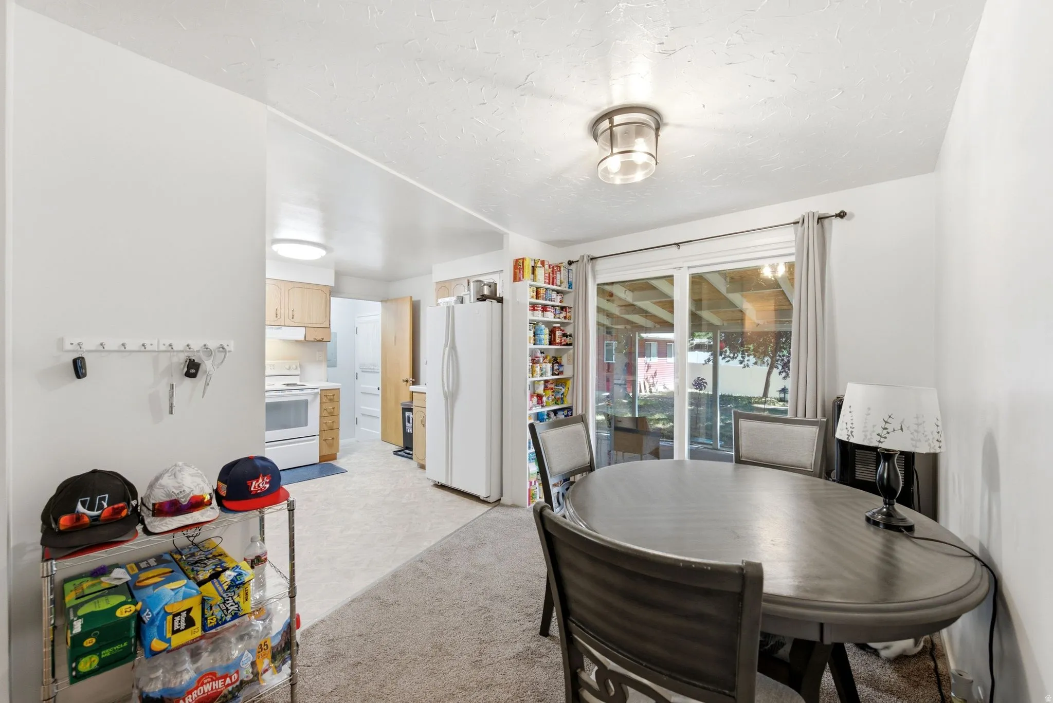 Dining area featuring a contemporary ceiling light fixture, sliding glass door, and neutral-toned wall-to-wall carpeting
