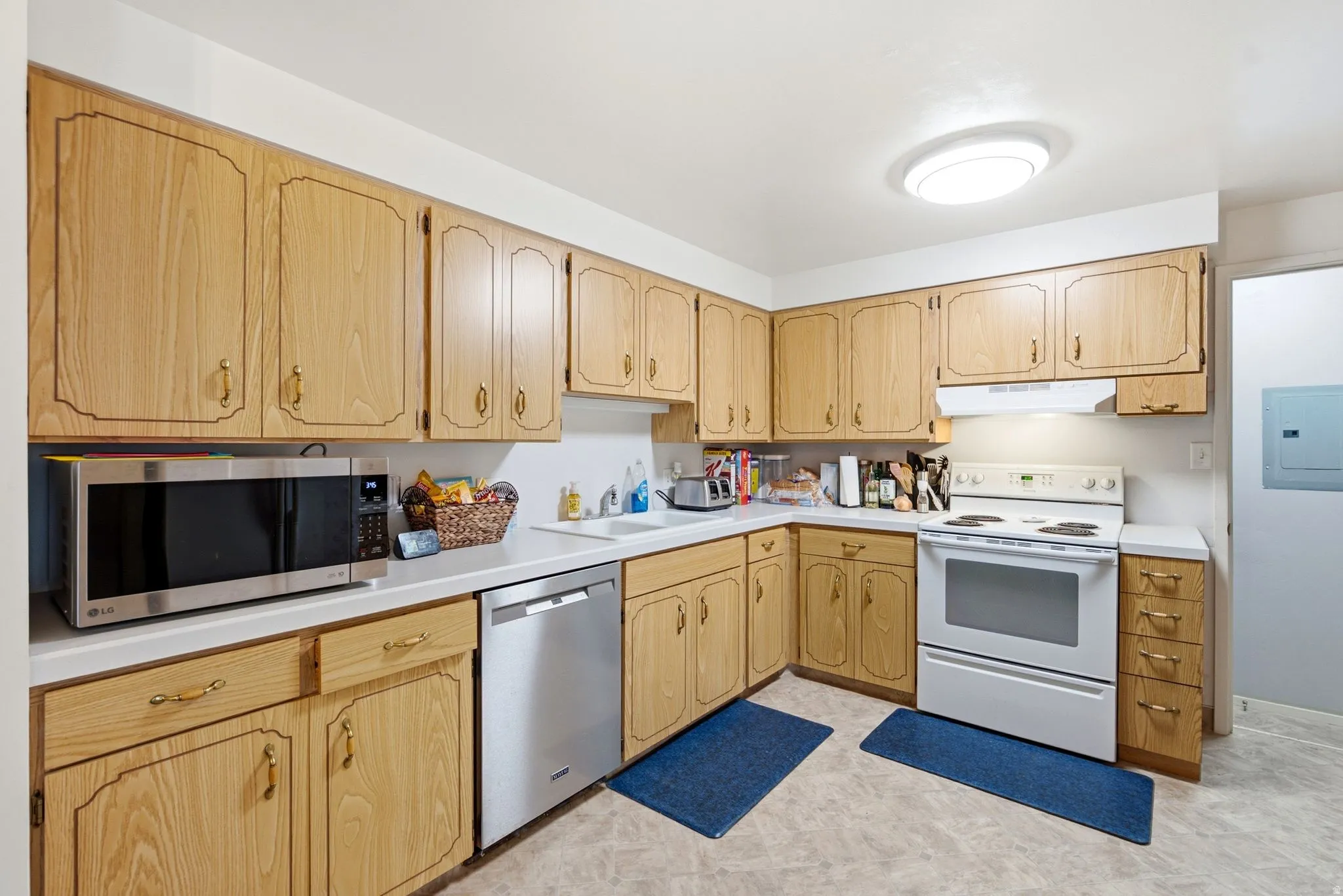 Kitchen featuring wood-finish cabinetry, white countertops, and a white electric range