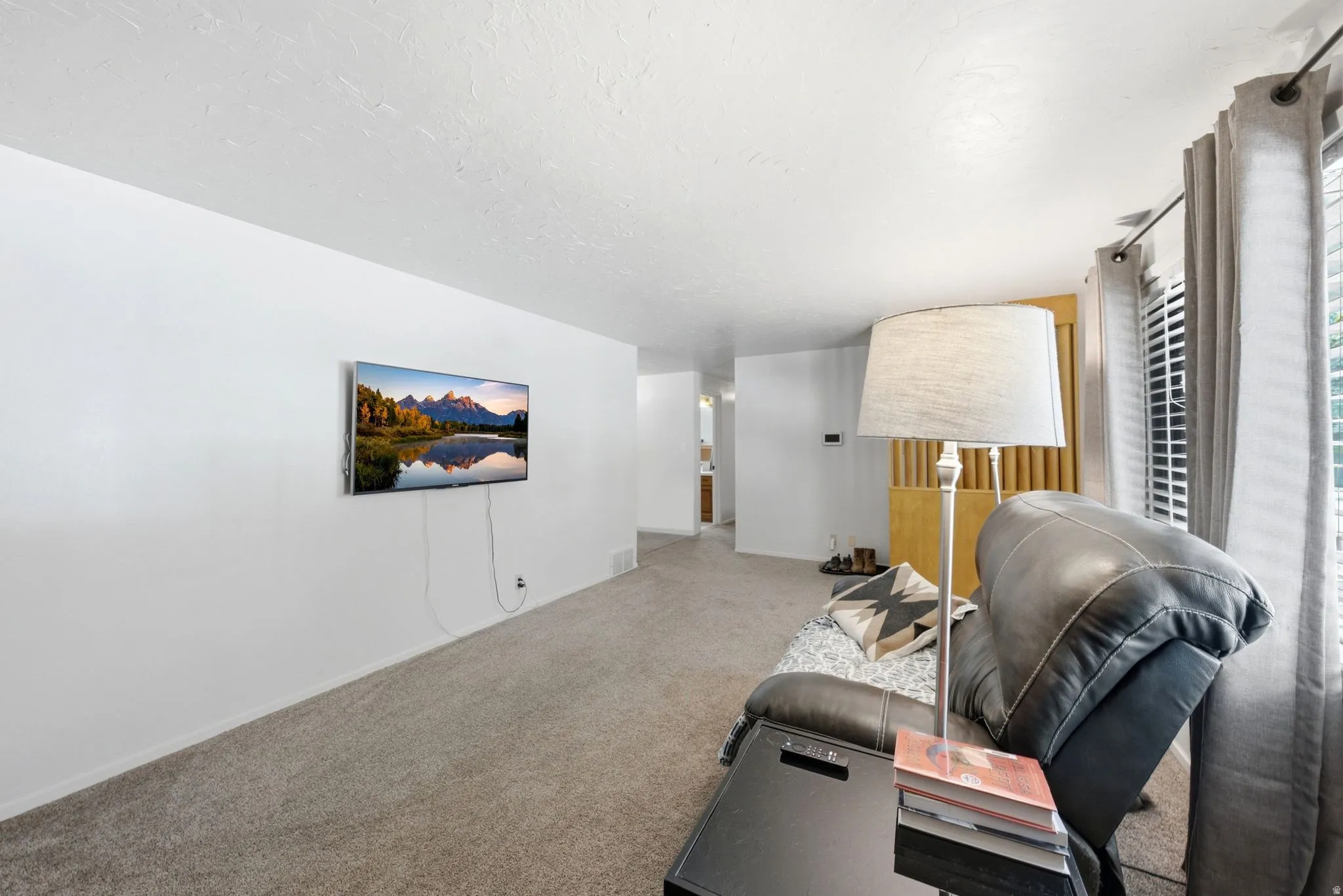 Carpeted interior space featuring white walls and a textured ceiling