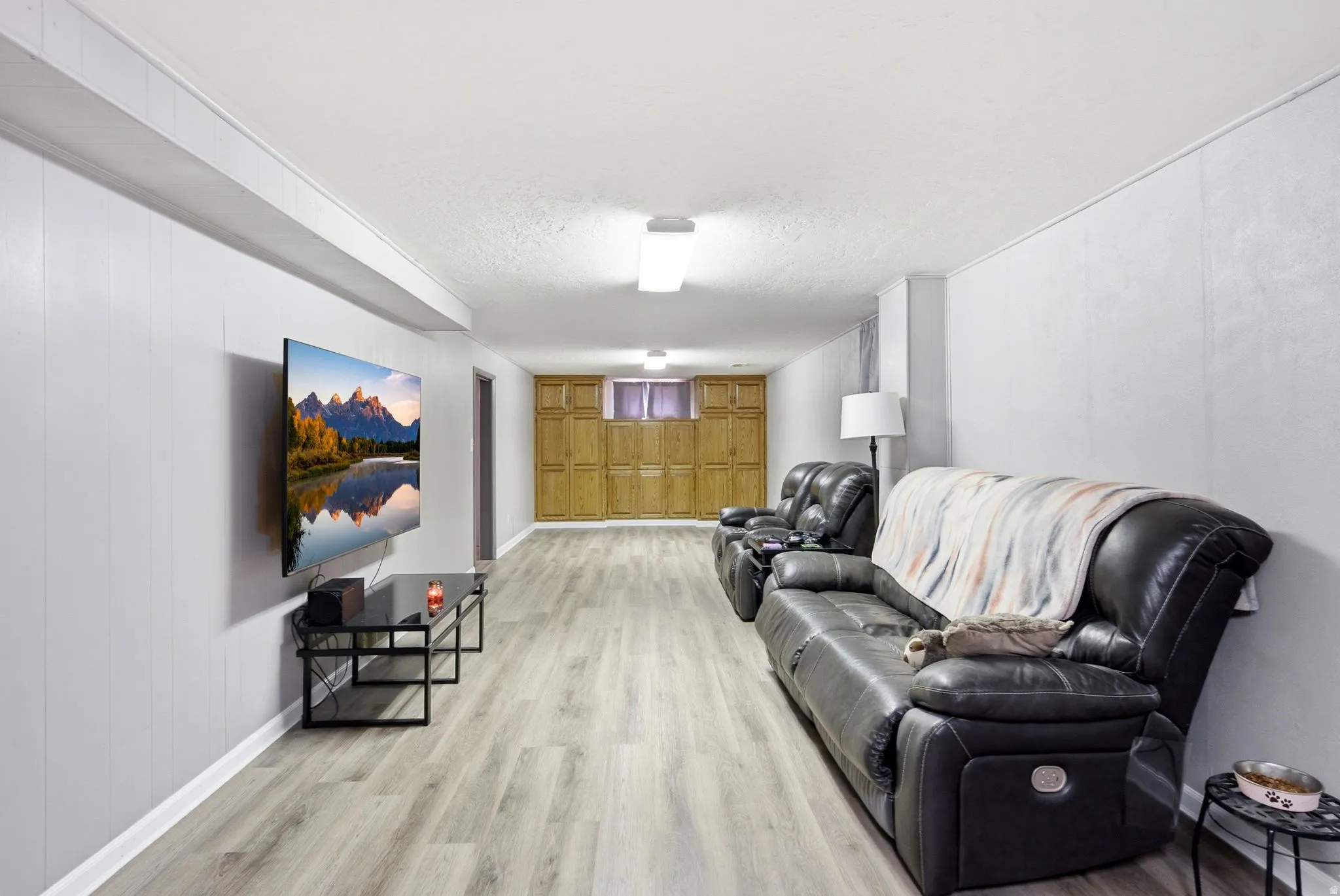 Finished lower level featuring recessed lighting, a built-in entertainment wall, and wood-finish flooring
