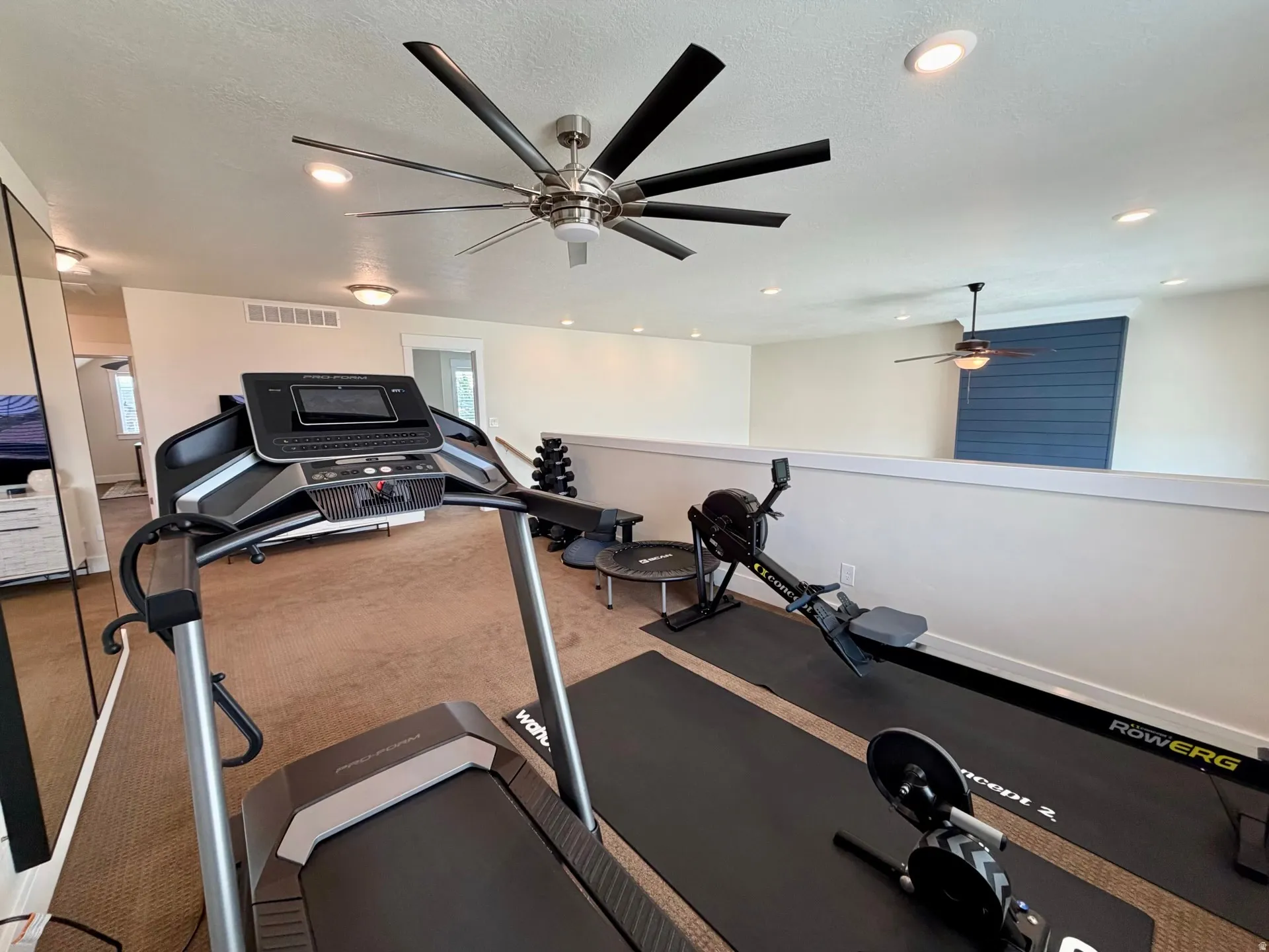 Open loft area featuring recessed lighting, ceiling fans, a partial wall, and a blue accent wall