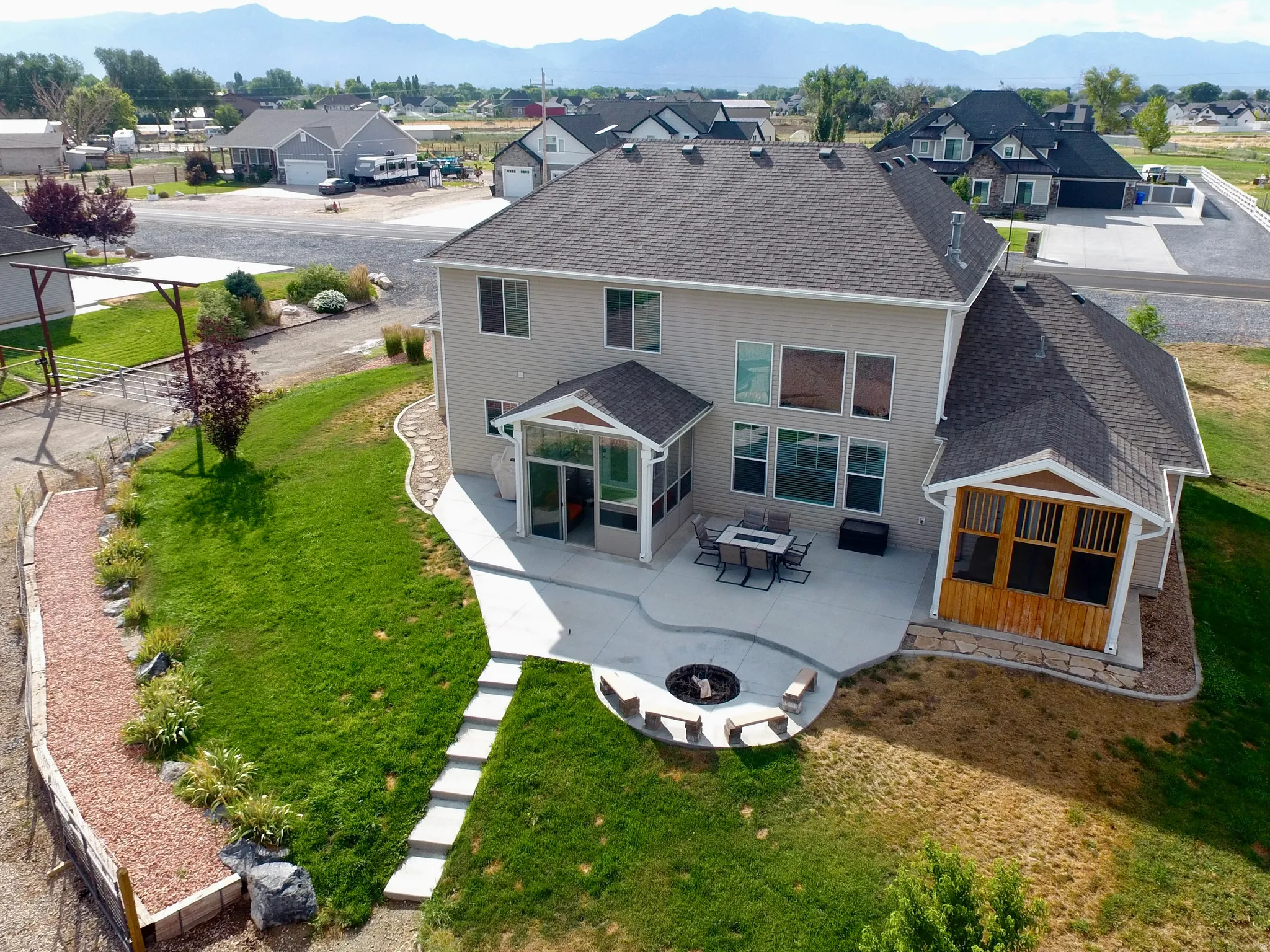 Spacious backyard featuring an extensive concrete patio, built-in fire pit with bench seating, and a covered screen porch