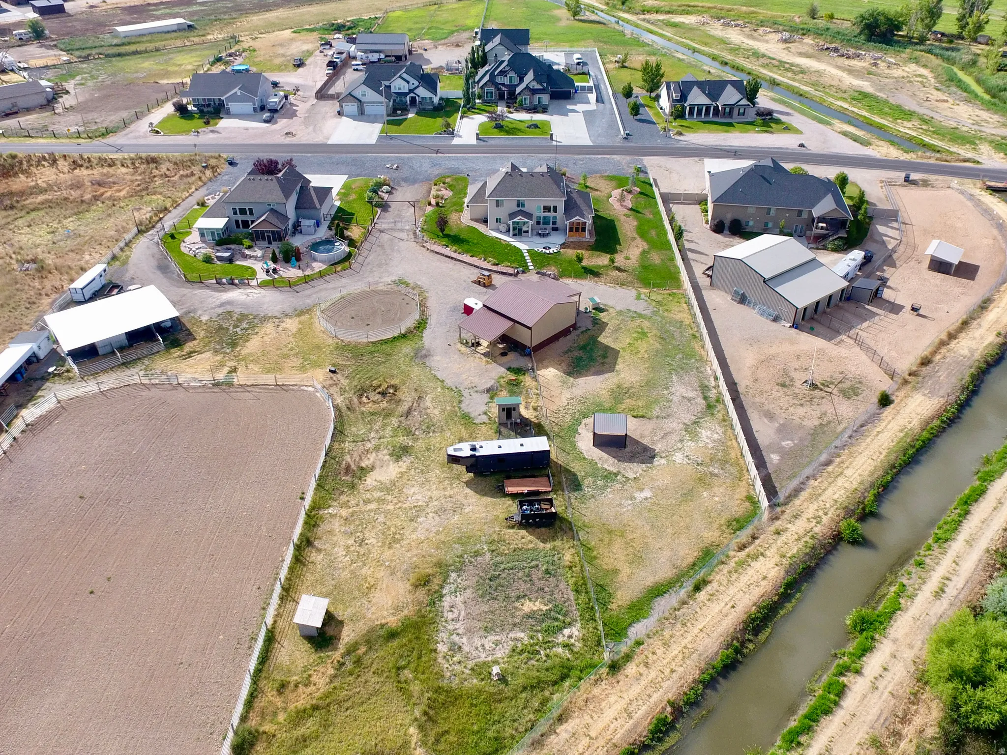 Expansive property featuring a large equestrian riding arena, multiple outbuildings, and a water canal border