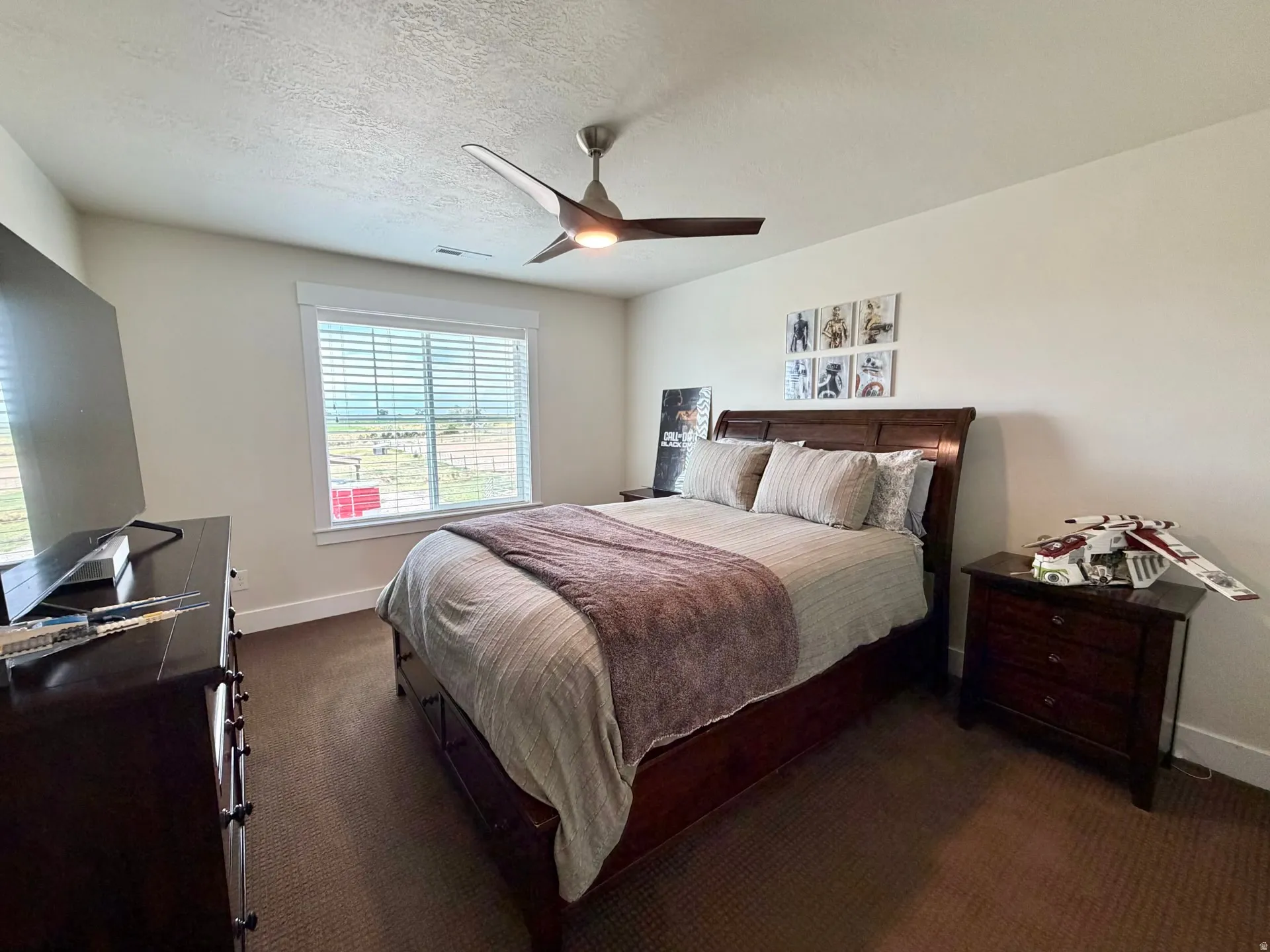 Bedroom featuring neutral wall paint, a ceiling fan with light fixture, and a large window with horizontal blinds