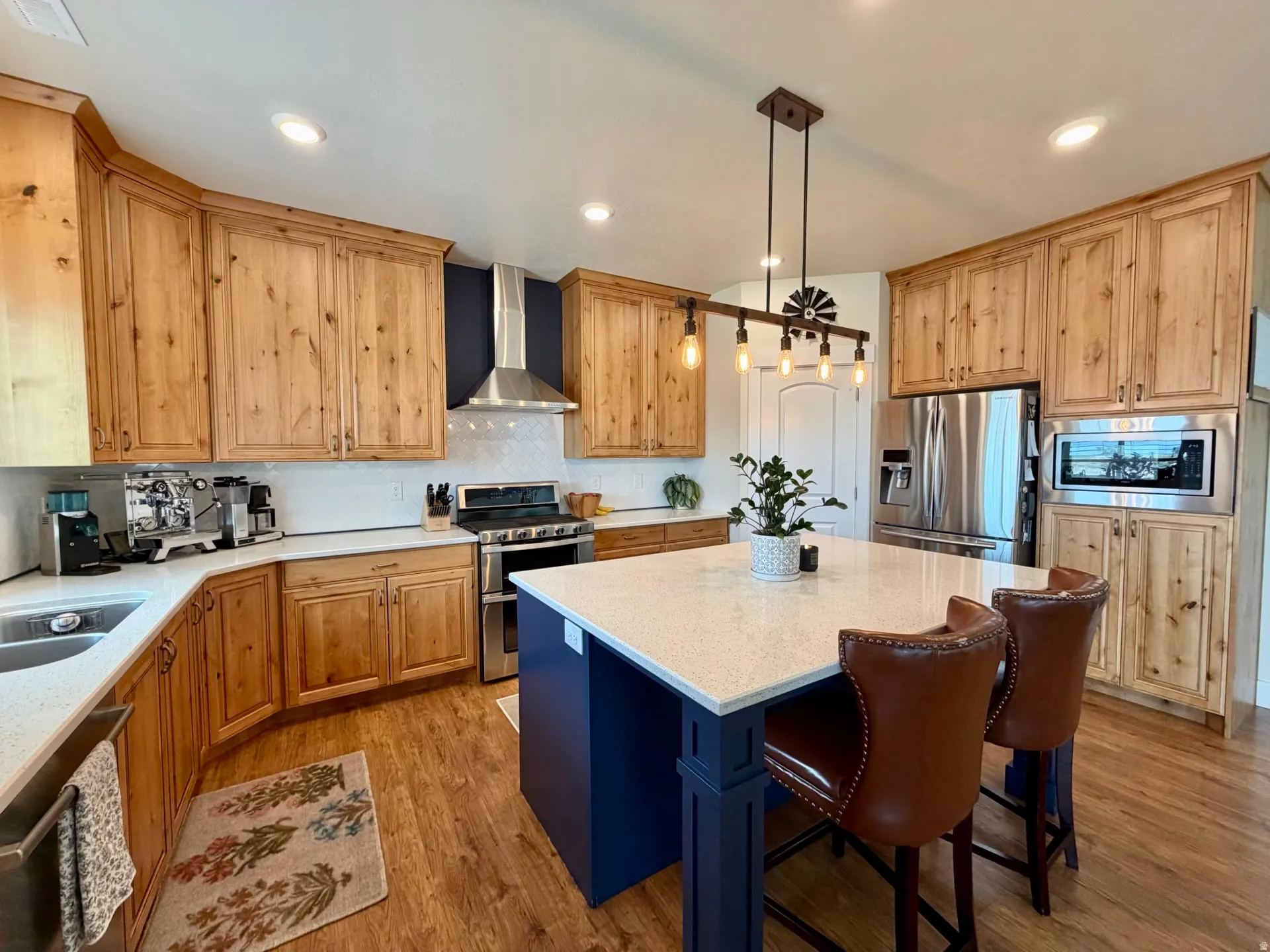 Kitchen featuring light wood cabinetry, white stone countertops, and wood-finish flooring