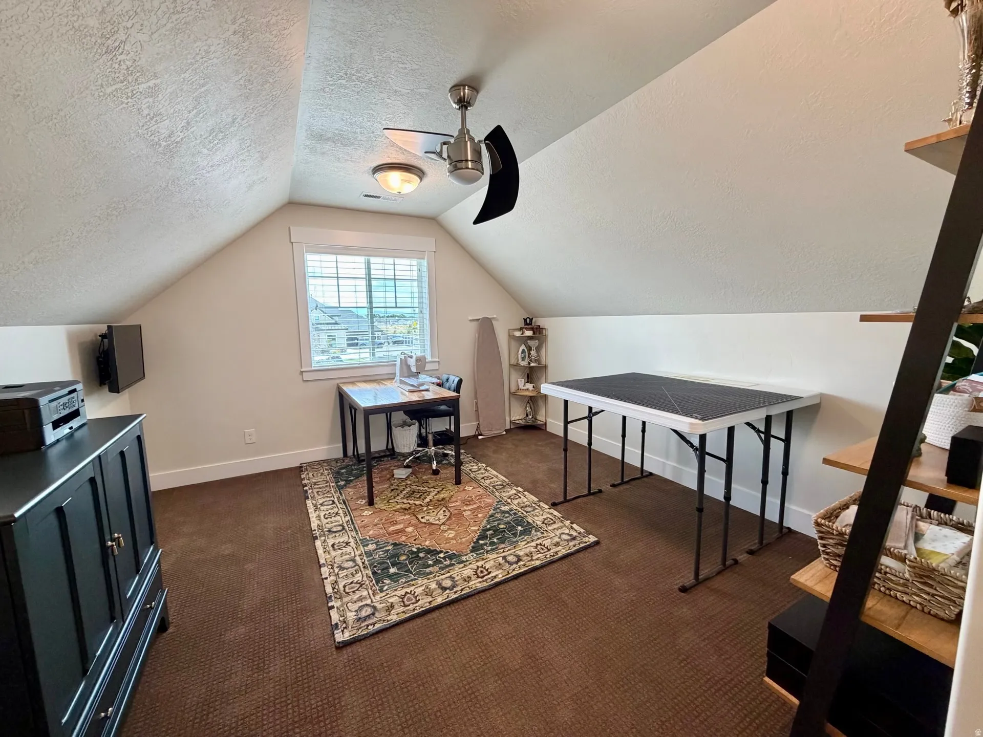 Attic room featuring sloped ceilings, a window with horizontal blinds, and textured wall finishes