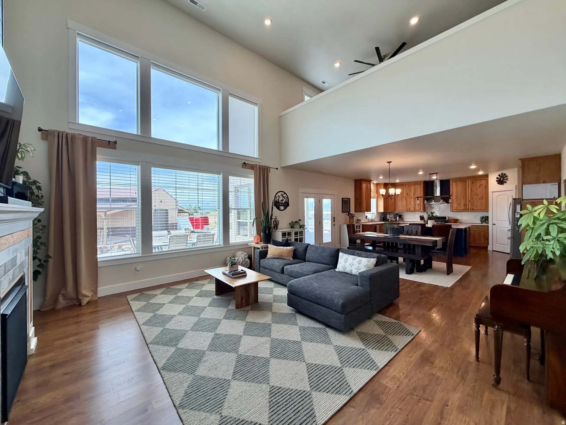 Vaulted ceilings define this open-concept living space, featuring wood-finish flooring and a stone-faced fireplace
