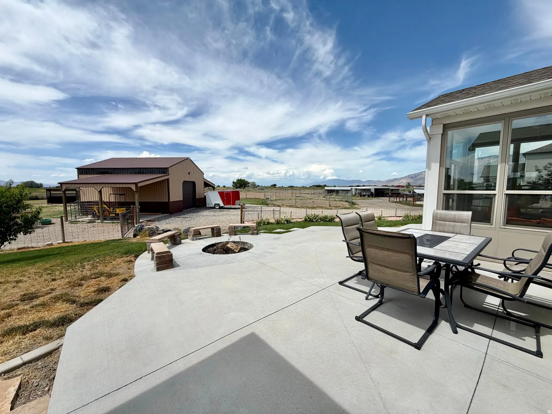 Expansive concrete patio featuring a built-in fire pit with stone seating