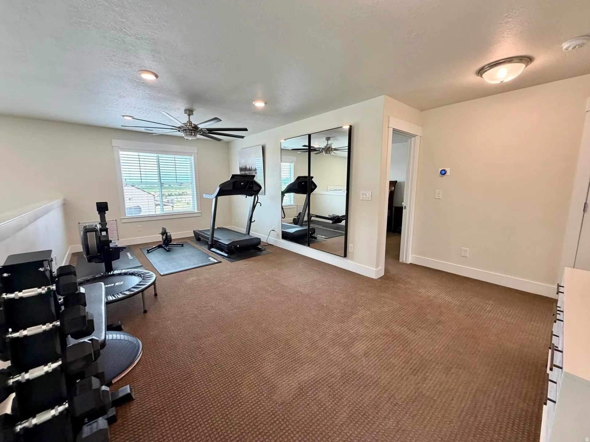 Versatile bonus room featuring neutral carpet flooring, a large window with horizontal blinds, recessed lighting, and a ceiling fan