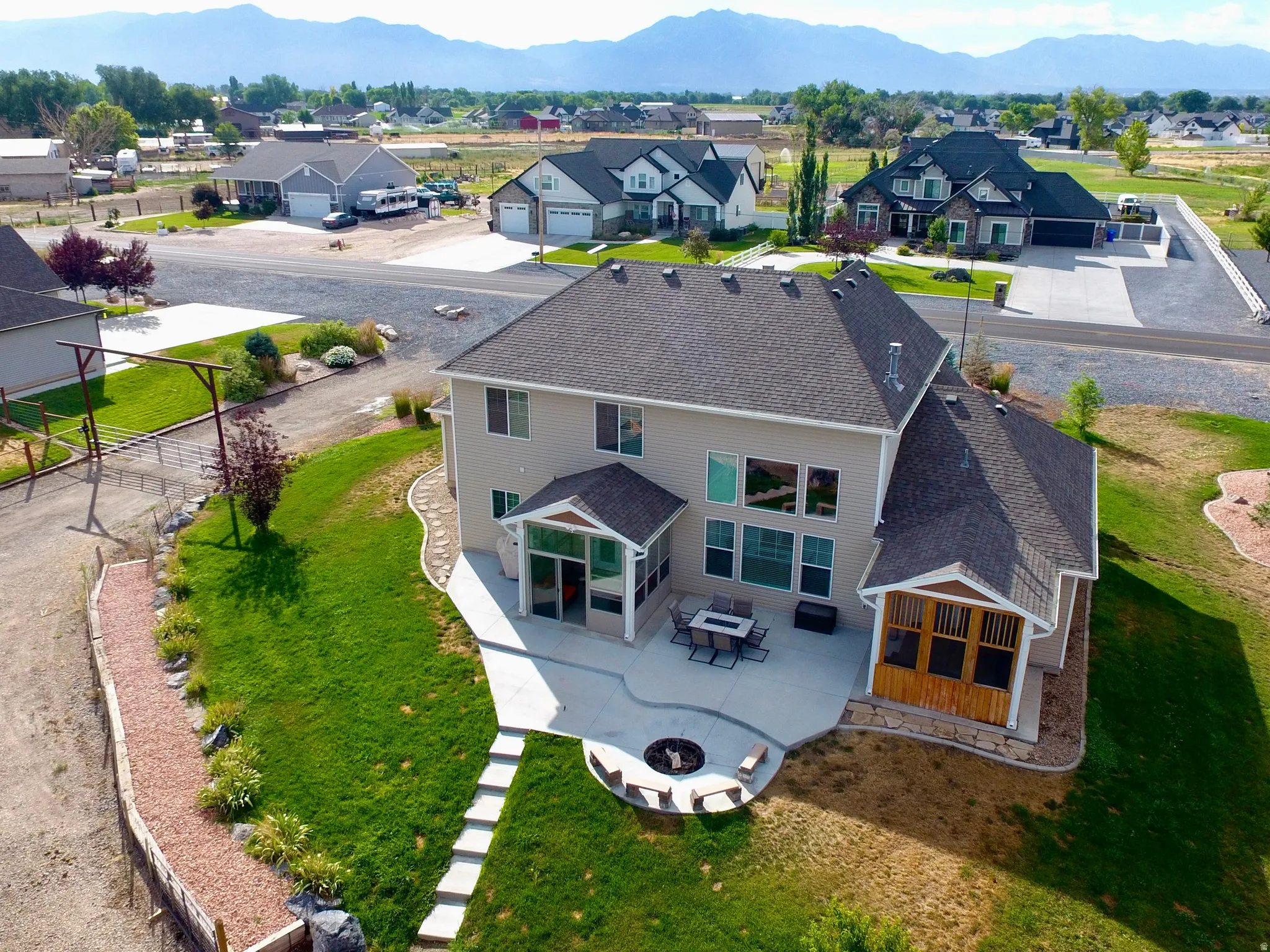 Rear exterior showcasing a spacious concrete patio with a built-in fire pit