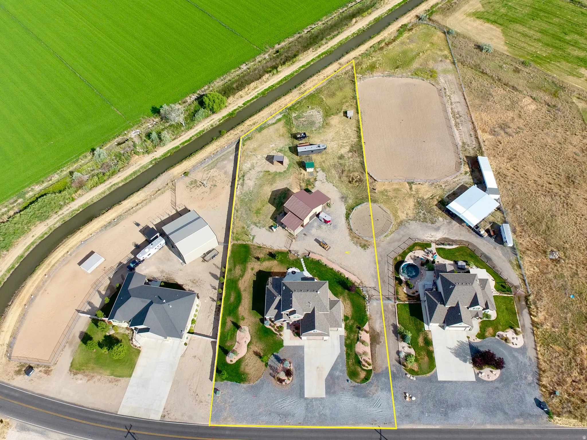 Expansive property featuring a paved driveway, detached garage, and a large arena