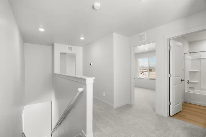 Bright, open hallway featuring recessed lighting, white painted walls, and wood-finish flooring