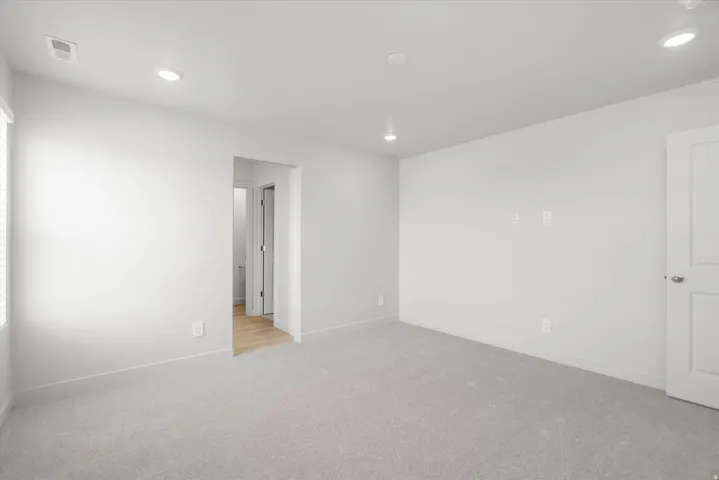 Recessed ceiling lighting with a flat white ceiling, white walls, and light-toned carpeting