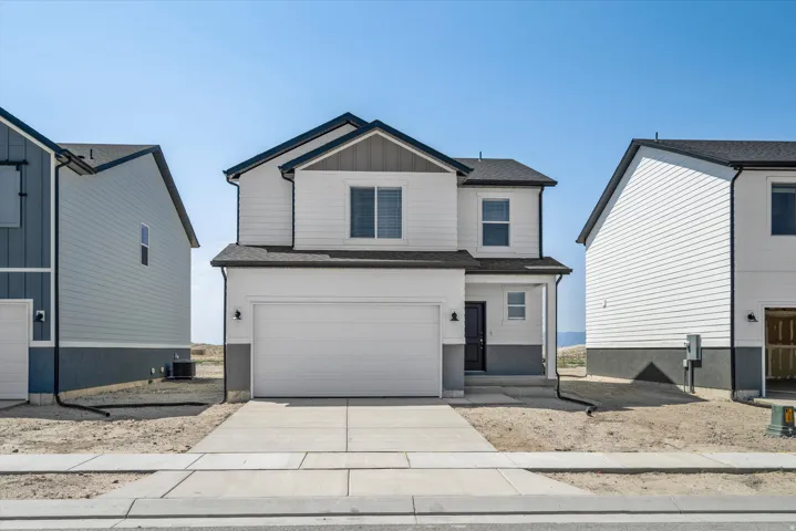 Two-story home featuring a clean contemporary exterior with light-colored siding, a two-car garage, and a wide concrete driveway