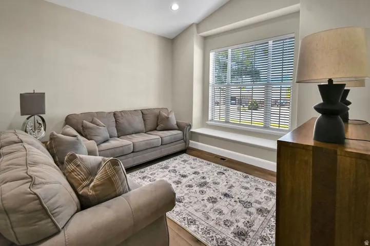 Room featuring high vaulted ceilings, large window with blinds, and a window seat