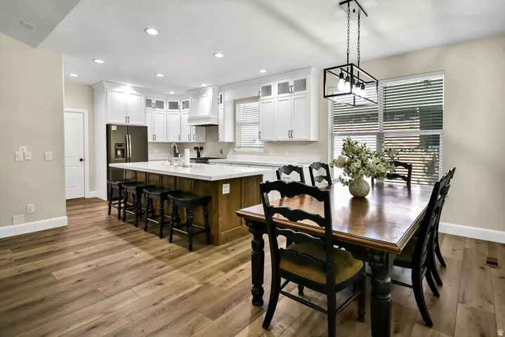 Open-concept kitchen featuring white cabinetry, a central island with bar seating, and stone-finish countertops