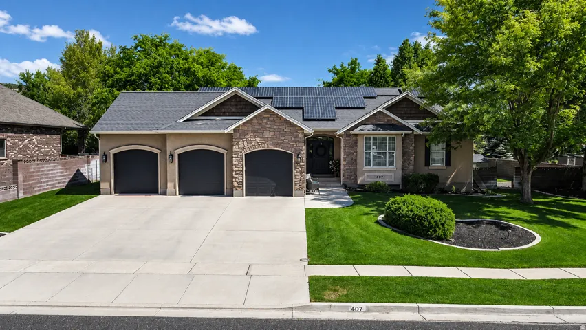 Stone and stucco exterior with a three-car garage and concrete driveway