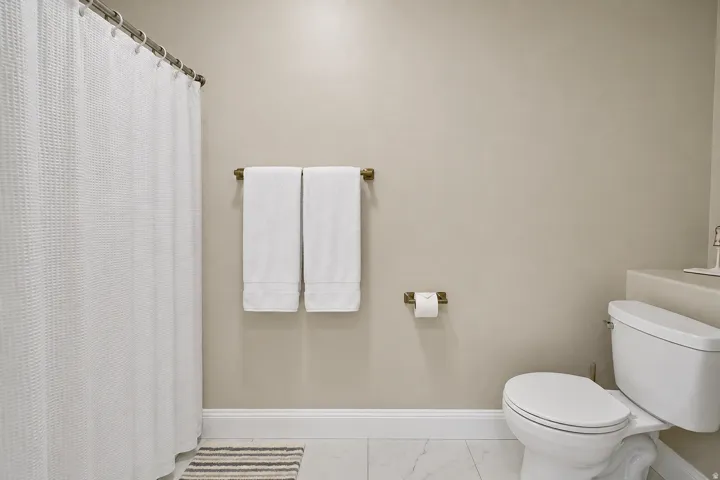 Bathroom featuring light neutral wall paint, white baseboards, and white tile flooring