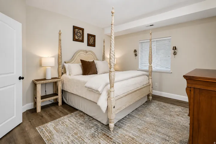 Bedroom featuring wood-finish flooring, neutral wall paint, and a window with blinds