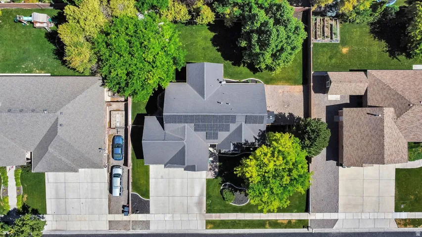 Aerial perspective showcasing a property with a grey shingle roof and integrated solar panel array