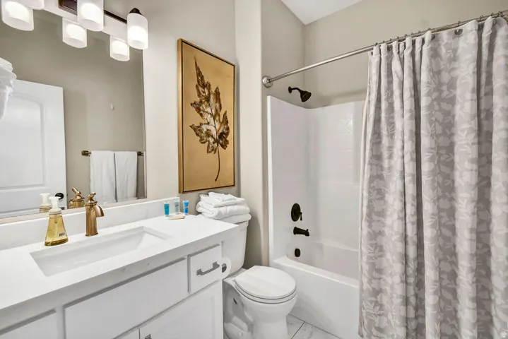 Bathroom featuring a white vanity with an integrated sink, polished gold-tone faucet, and an overhead vanity light fixture