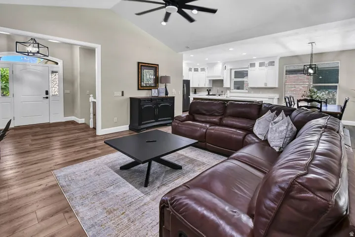Open-concept living area featuring vaulted ceilings, wood-finish flooring, and a modern ceiling fan