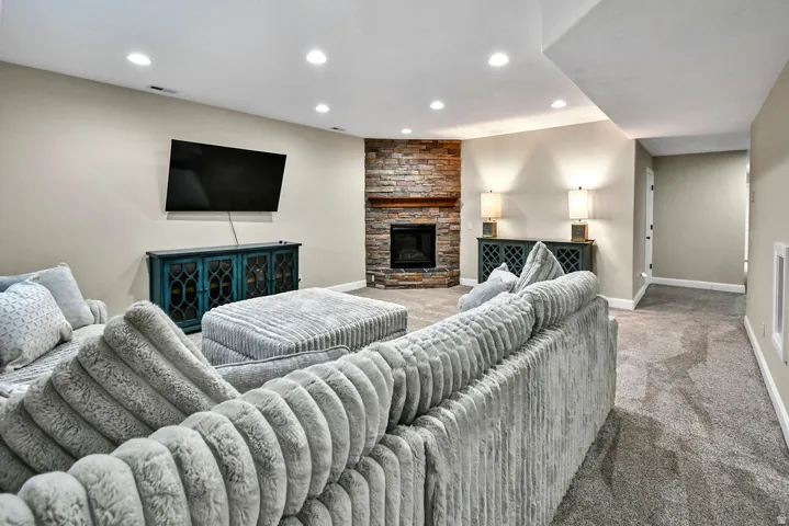 Spacious living area featuring a corner stone-front fireplace with a wood mantel