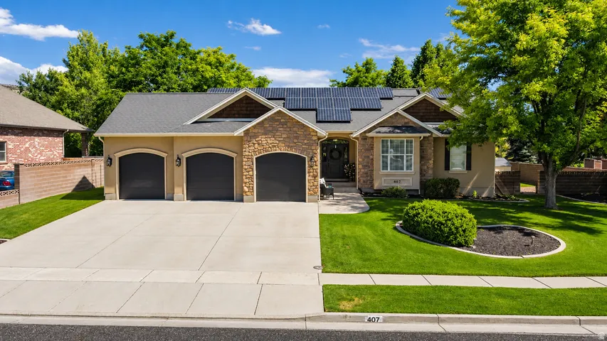 Single-story residence featuring a stucco and stone exterior, a three-car garage with arched entrances, a concrete driveway, an asphalt shingle roof with solar panels, and mature landscaping